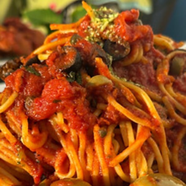 Close-up of spaghetti with red sauce, black olives, and green herbs, from Philly Pizza Authority.