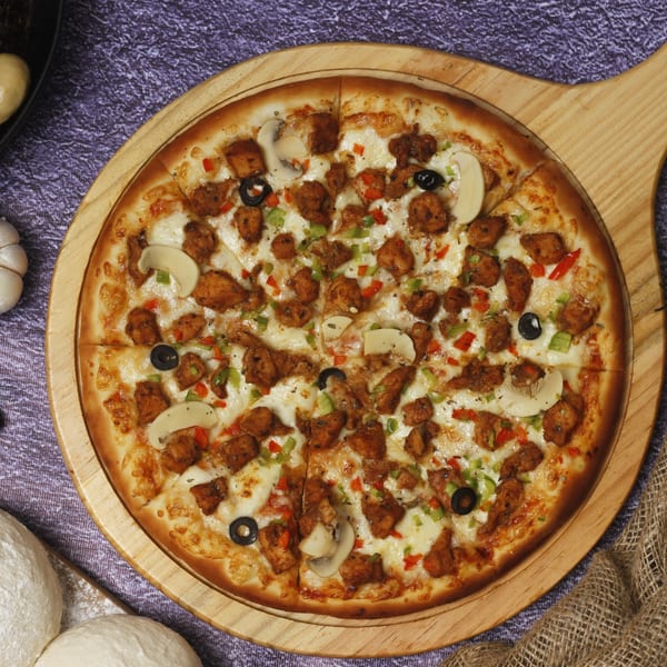 Philly Pizza Authority's chicken pizza, topped with mushrooms, olives, and bell peppers on a wooden board.
