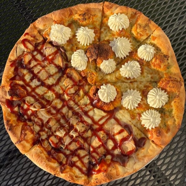 A Philly Pizza Authority pizza, half with BBQ chicken and half with white dollops on a green base.
